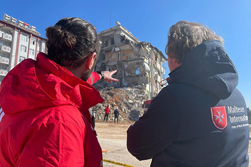 Zwei Männer betrachten eingestürztes Haus