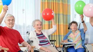 Ältere Menschen halten einen Luftballon in die Luft.