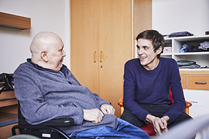 Junger Mann besucht älteren Mann im Hospiz