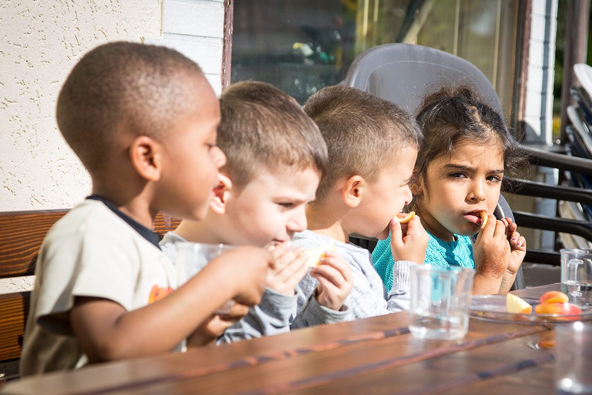 Vier Kinder essen zu Mittag im Familienzentrum Manna