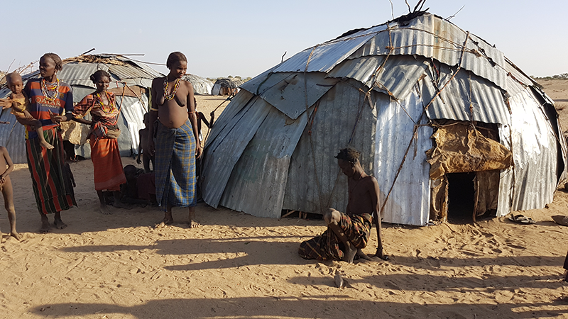 Ein Mann sitzt kraftlos durch Hunger vor seiner Hütte in Kenia
