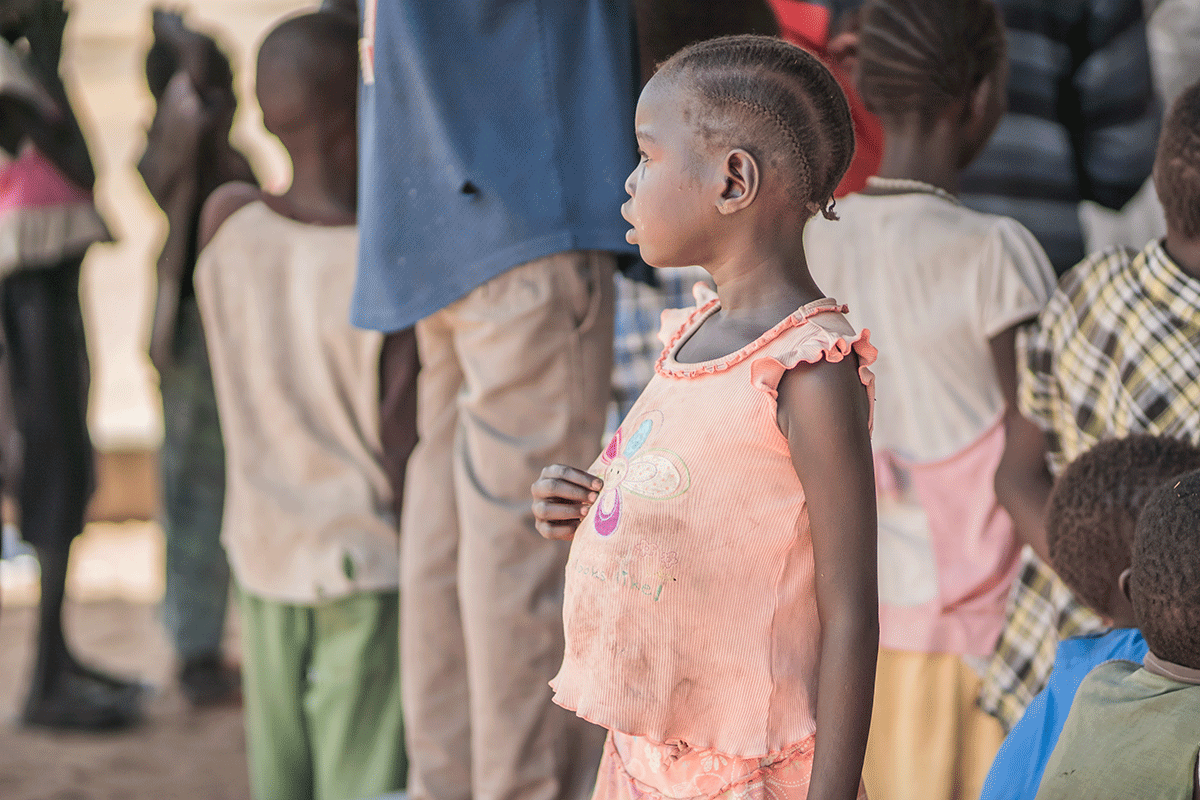 Mädchen aus Ostafrika im schmutzigen Shirt mit dünnen Armen und aufgeblähtem Bauch
