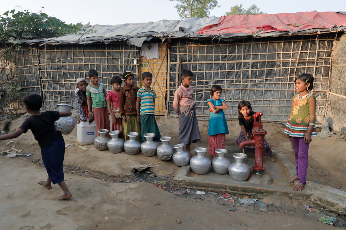 Kinder der Rohingya stehen am Brunnen im Flüchtlingslager für Wasser an