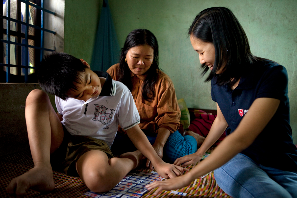 Junge mit Behinderung aus Vietnam mit Betreuerin der Malteser