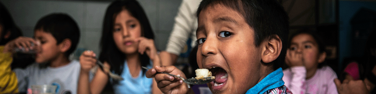 Junge aus Peru isst in der Suppenküche