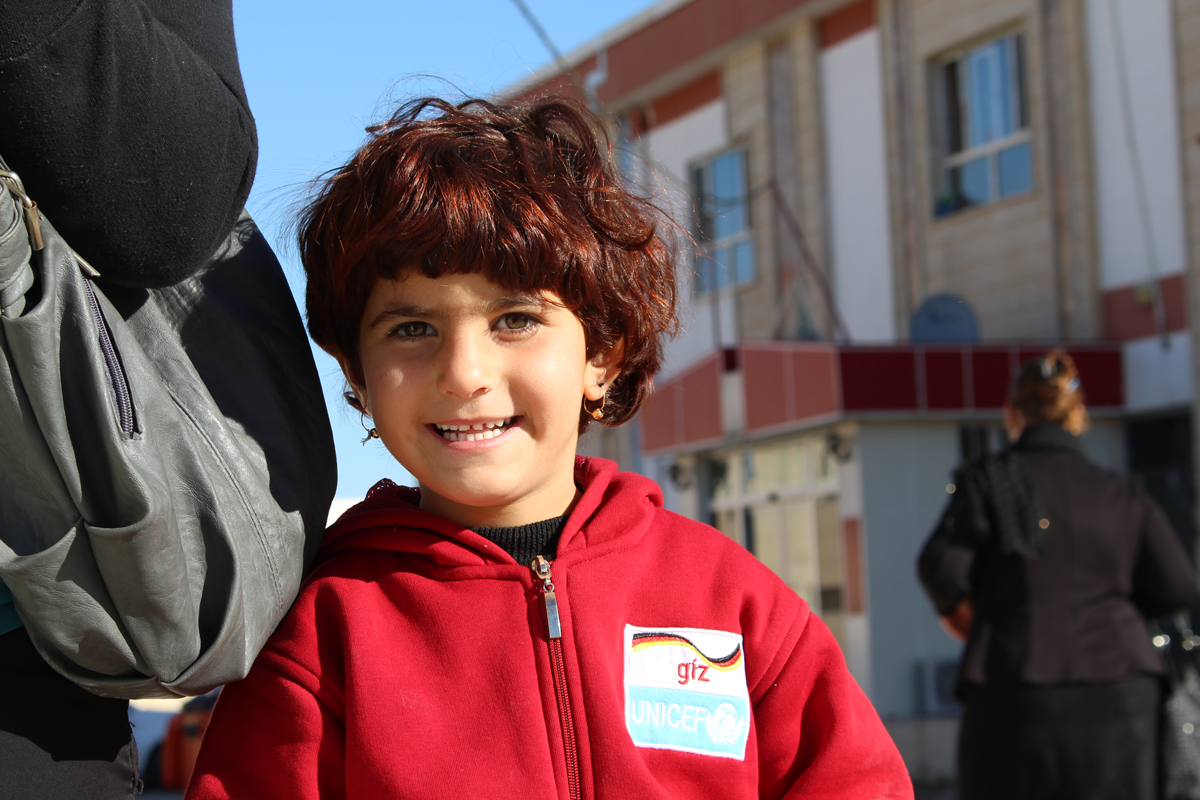 Ein Kinde aus dem Irak mit seinem neuen Pulli für den Winter