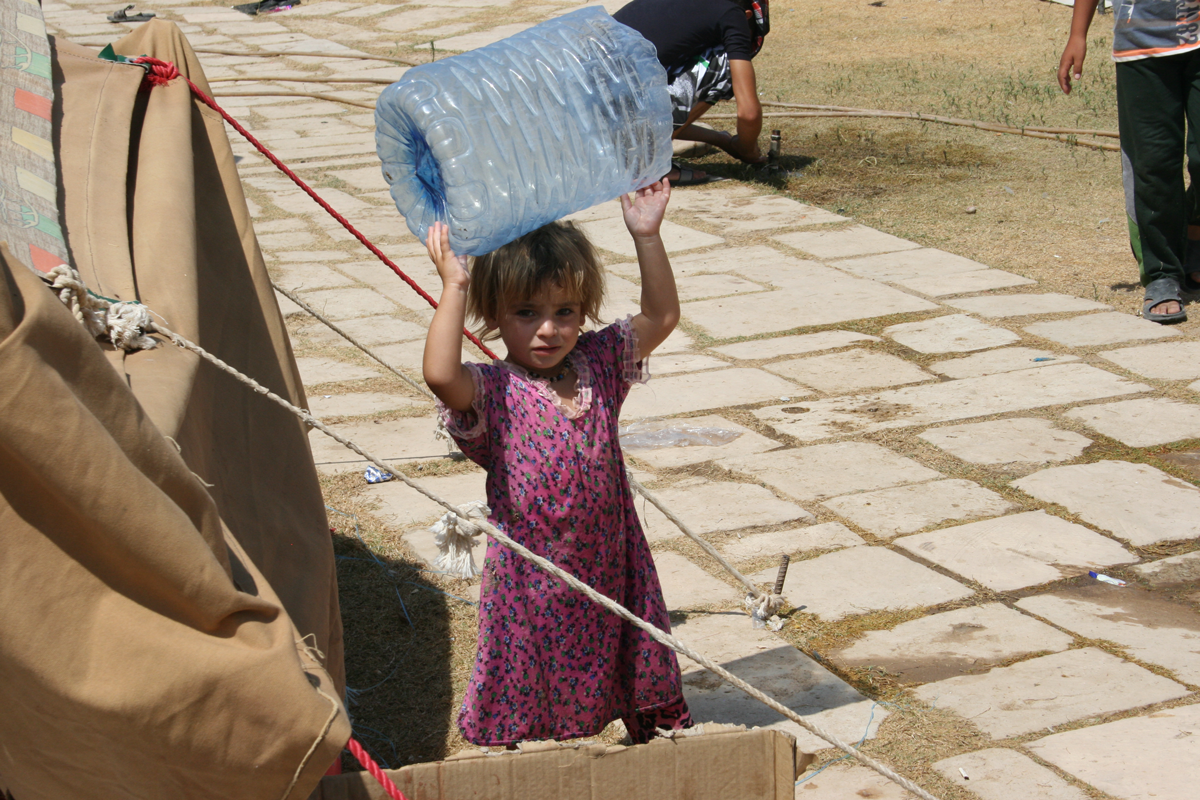 Kind aus dem Flüchtlingslager spielt mit Plastikflasche