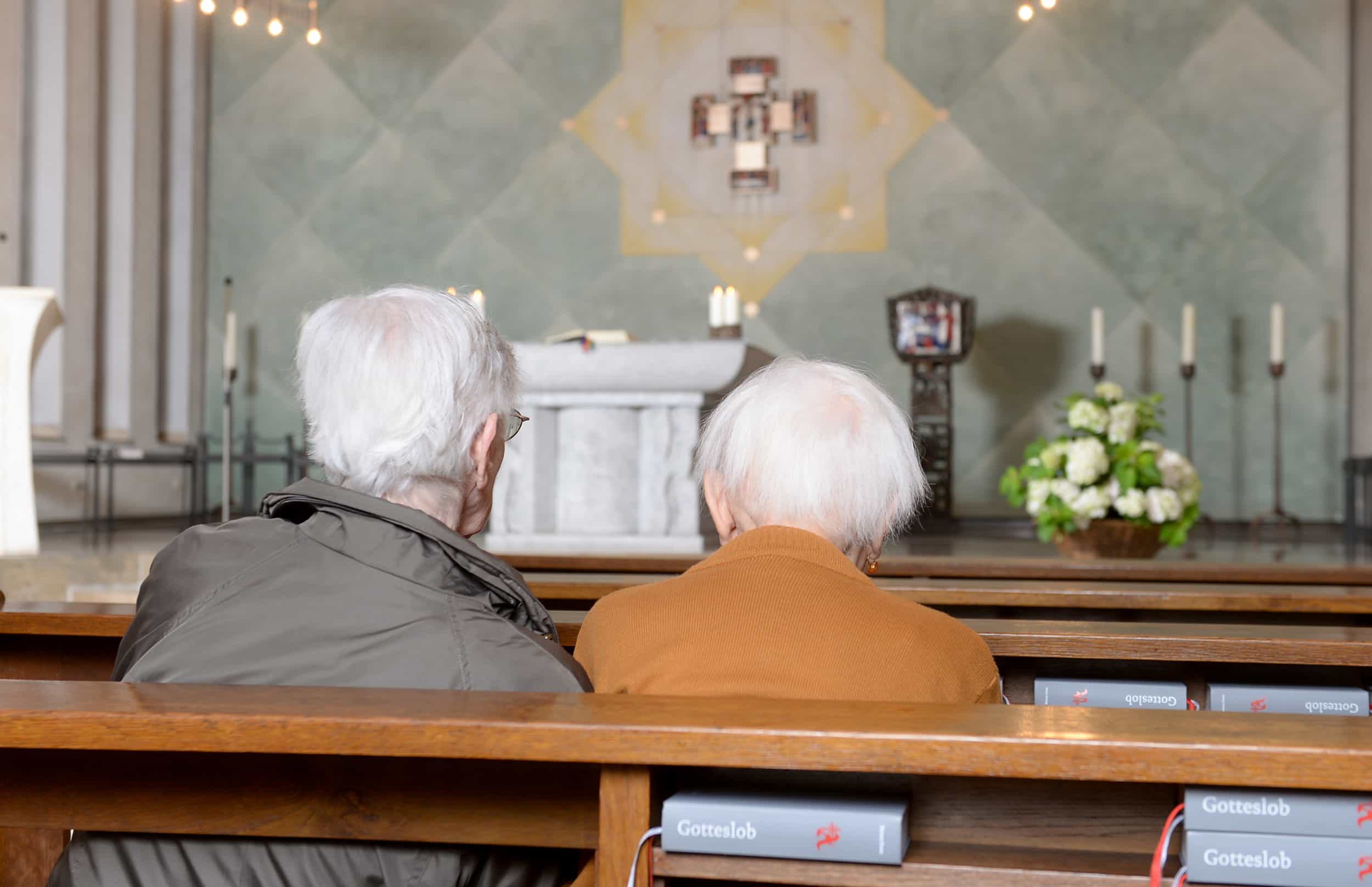 Zwei ältere Menschen sitzen in einer Kirche