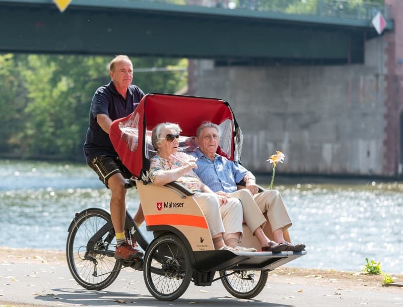 Zwei Senioren lassen sich in einer Rikscha fahren