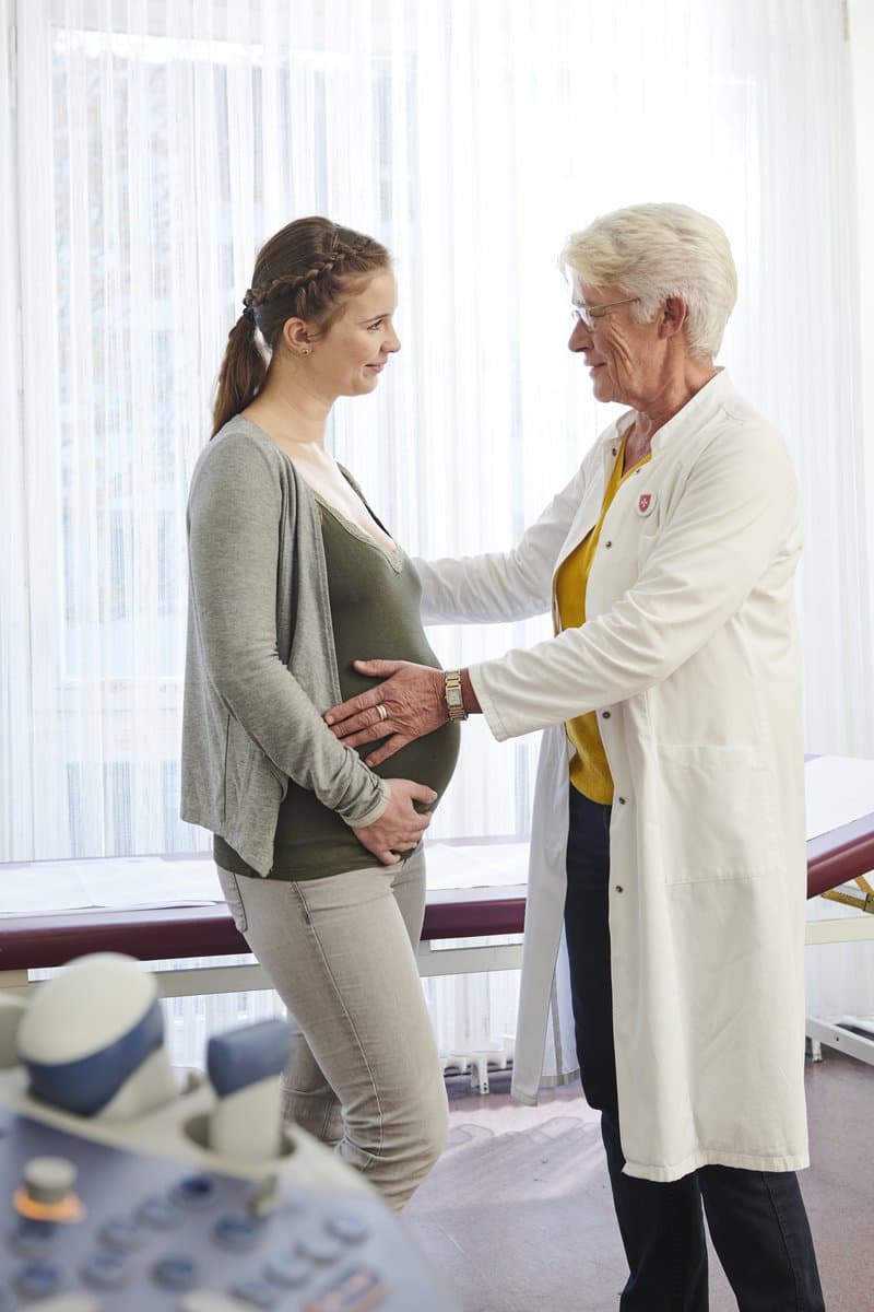 Eine Ärztin untersucht eine schwangere Frau. 
