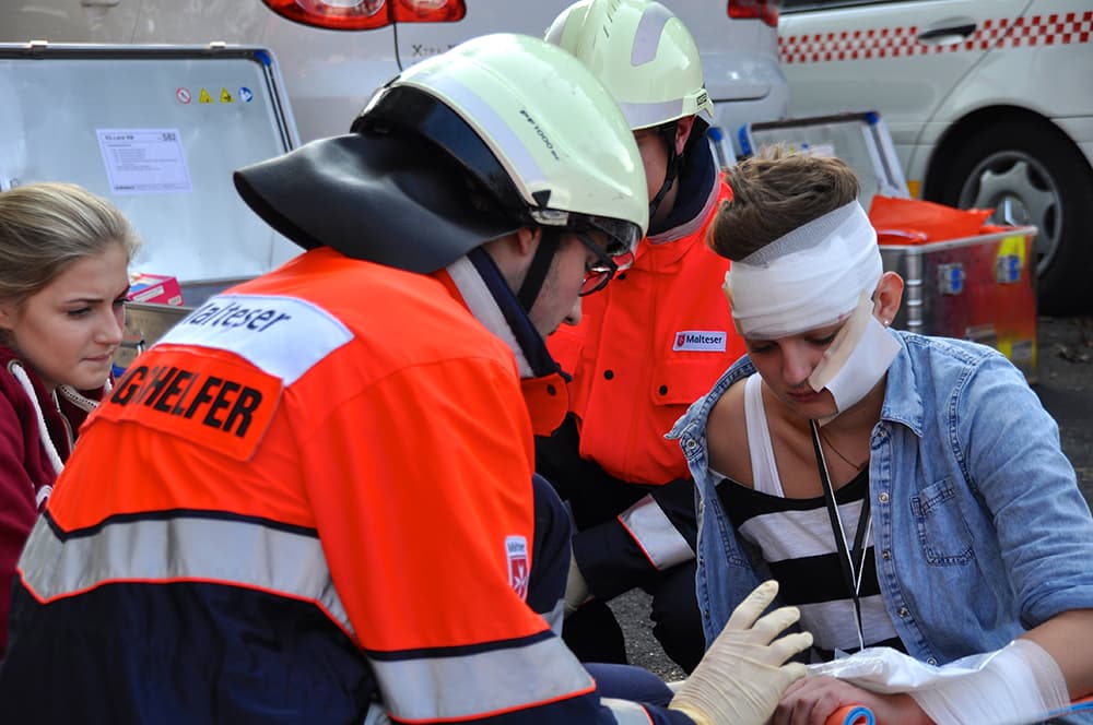 Die Mitarbeiter des Malteser Katastrophenschutzes helfen einem verletzten Mann.