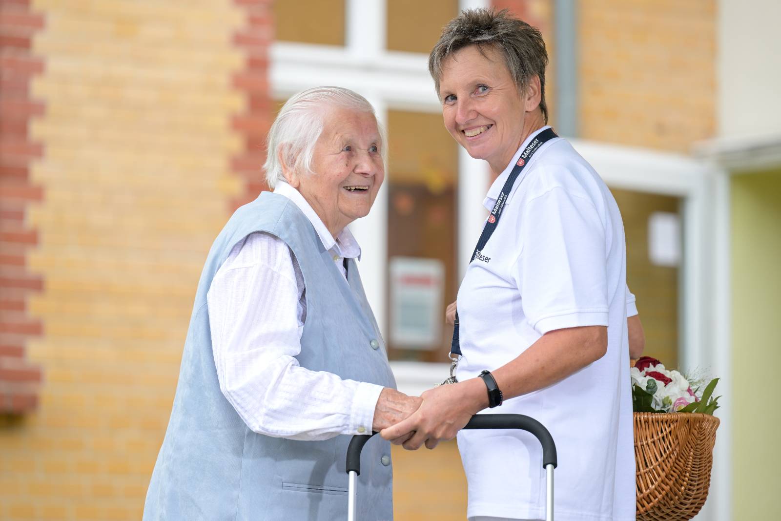 Pflegerin der Malteser hilft einer älteren Frau bei einem Spaziergang