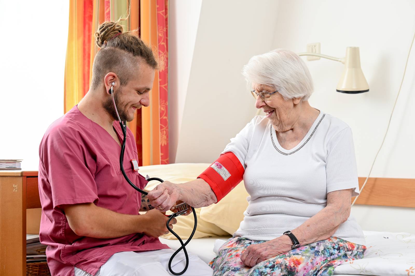 Altenpfleger der Malteser misst den Blutdruck einer Patientin