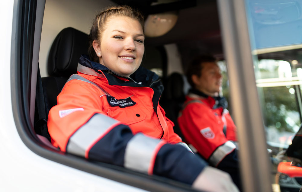 Es wird eine Malteser Notfallsanitäterin aus dem Rettungsdienstwagen gezeigt.