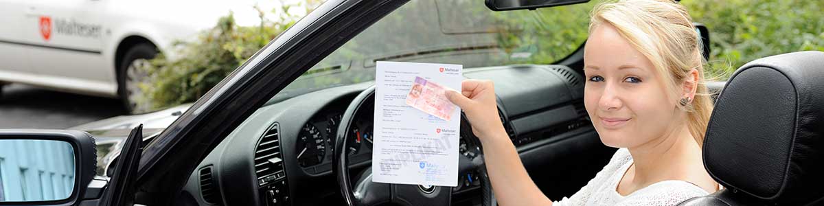 Eine Absolventin eines Malteser Erste-Hilfe-Kurses für Führerscheine sitzt nach bestandenem Kurs in ihrem Auto.