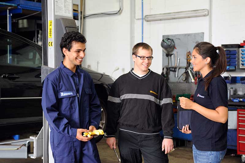 Malteser Ausbilderin bespricht den Erste-Hilfe-Kurs mit Mitarbeitern einer Autowerkstatt.