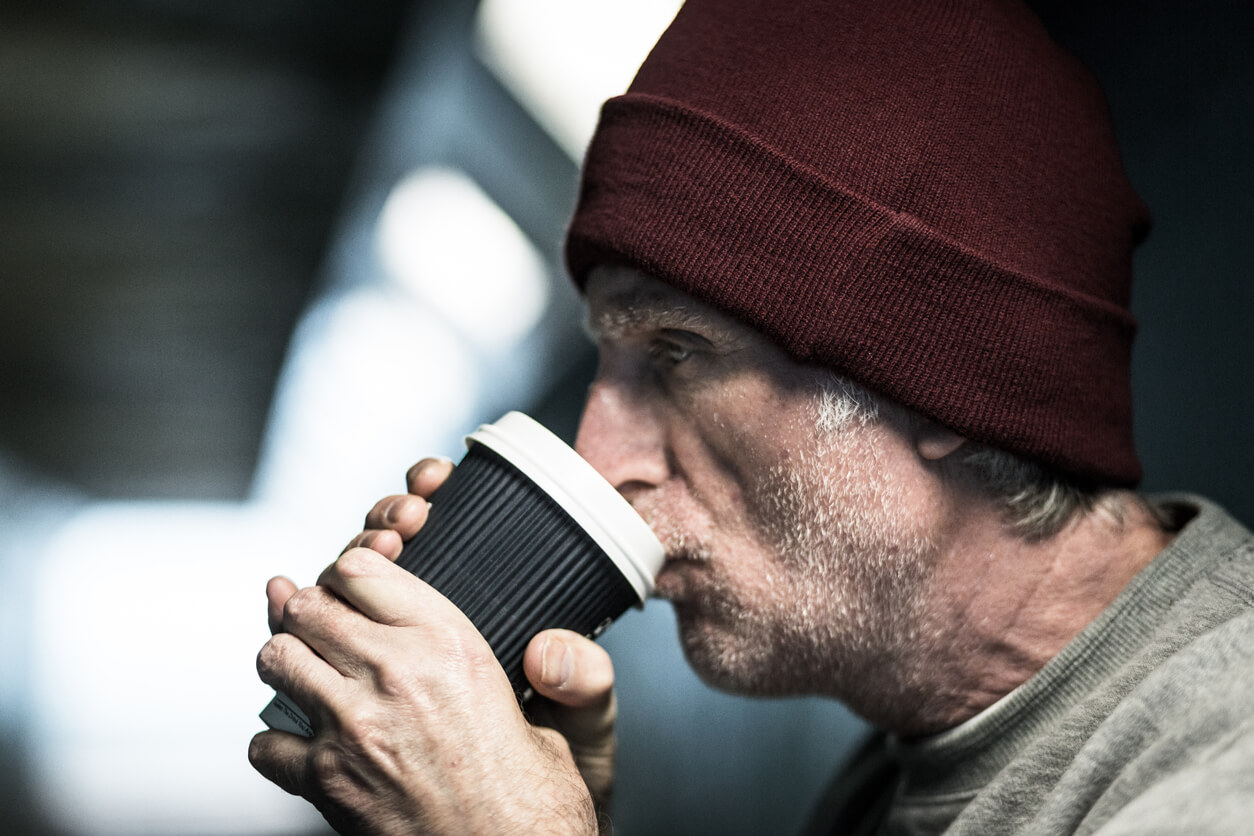 Obdachloser trinkt aus einem Becher