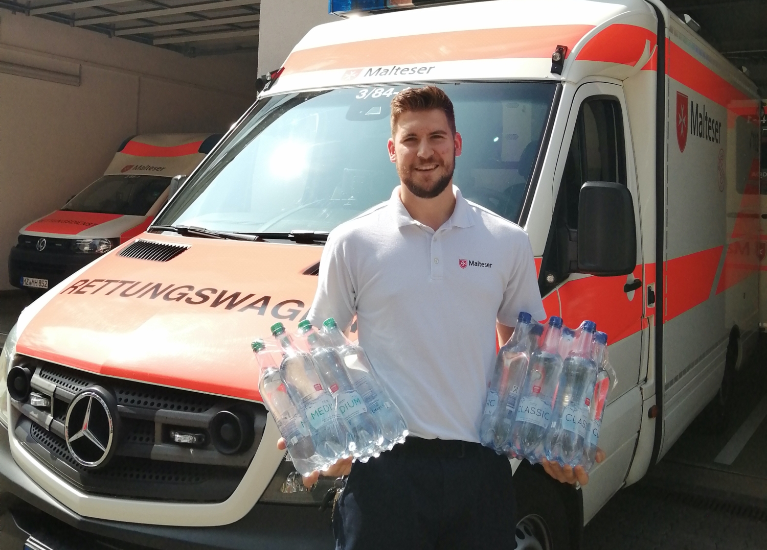 Mann mit Wasserflaschen vor Rettungswagen 