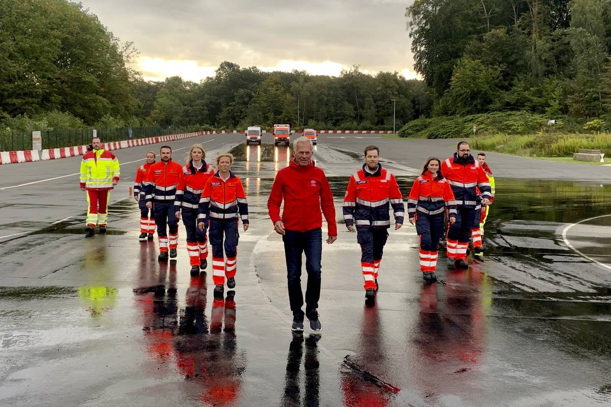 Formel-1-Fahrer Christian Danner und die Teilnehmer des Fahrsicherheitstraining laufen über eine Fahrbahn