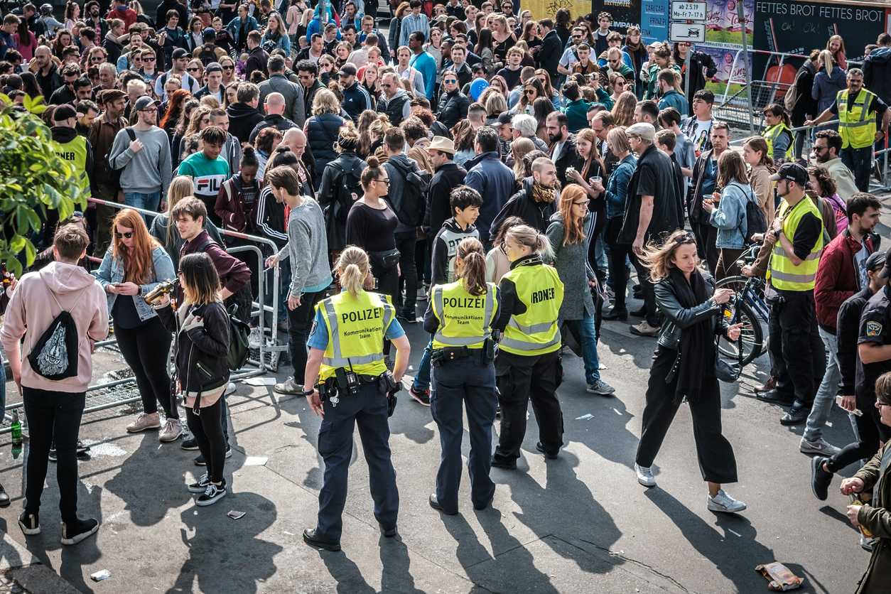 Eine Menschenmenge und Polizistinnen in gelben Warnwesten