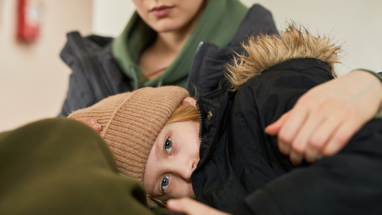 Ein Kind in Winterkleidung liegt auf dem Schoß einer Frau