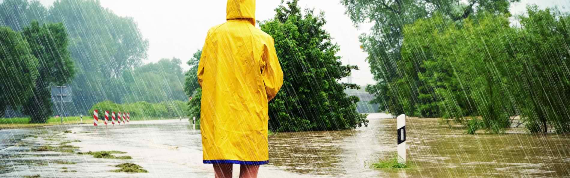 Eine Person in einem gelben Regenmantel in einer überschwemmten Landschaft