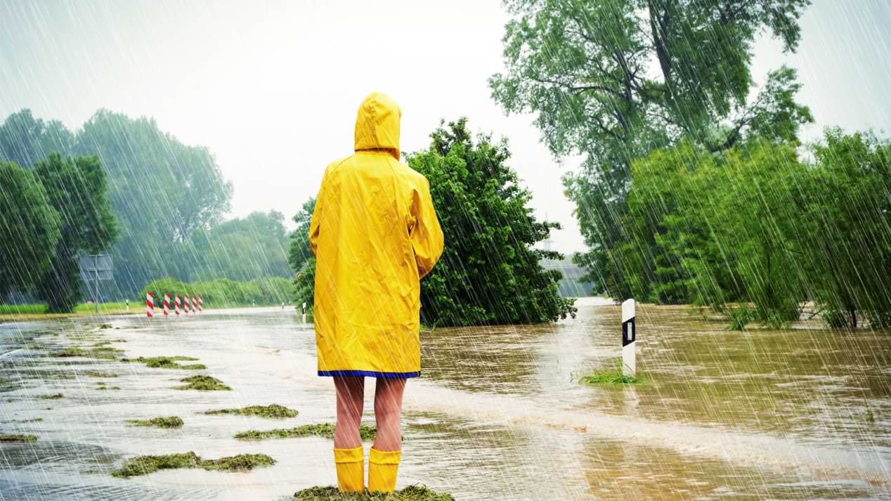 Eine Person in einem gelben Regenmantel in einer überschwemmten Landschaft