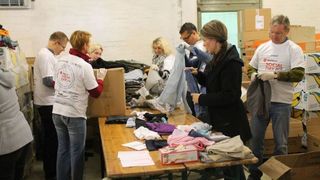 Mitarbeiter beim Social Day helfen in einer Kleiderkammer.