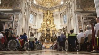 Malteser Betreuer und Menschen im Rollstuhl in einer Kirche. 