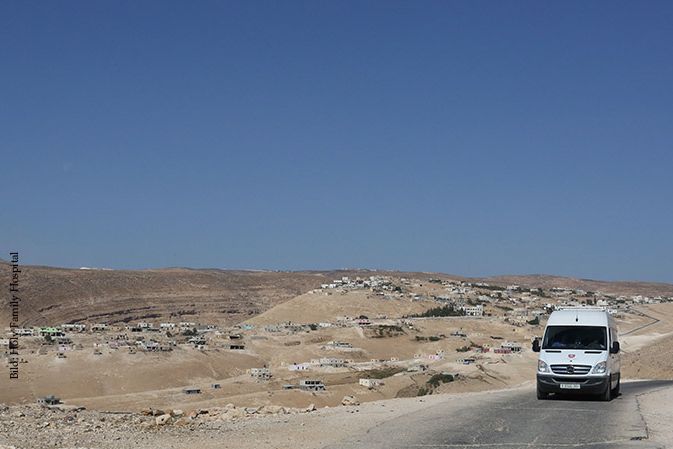 Ein weißer Kleinbus fährt durch die Wüste