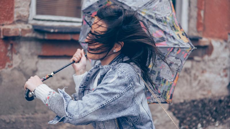 Eine Frau mit Regenschirm bei starkem Wind