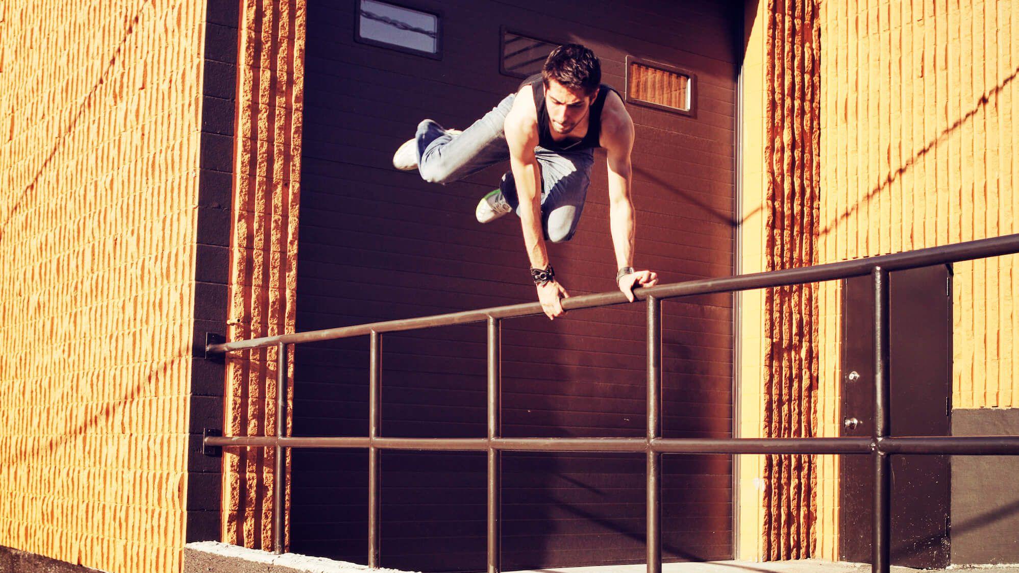 Junger Mann springt über Geländer in urbanem Umfeld