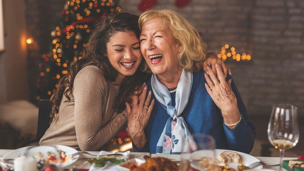 Zwei Frauen lachen zusammen während des Weihnachtsessens.