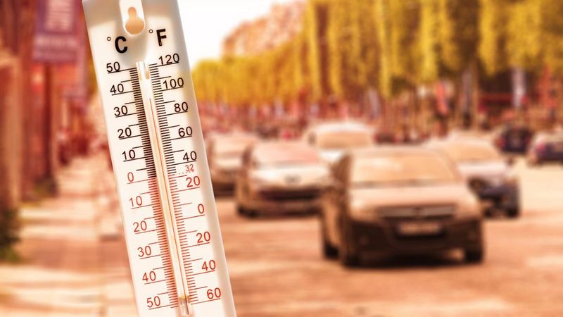 Ein Thermometer im Vordergrund mit Autos im Hintergrund