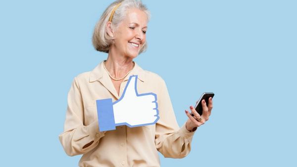 Eine ältere Frau mit einem Smartphone und einem Facebook-Daumen.
