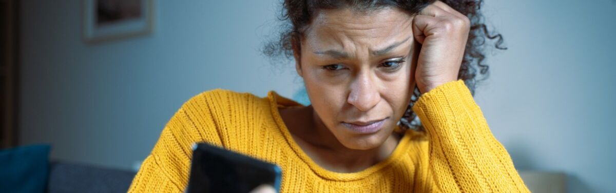 Junge Frau mit besorgtem Gesichtsausdruck schaut auf ein Smartphone