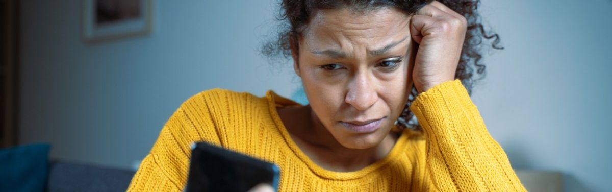 Junge Frau mit besorgtem Gesichtsausdruck schaut auf ein Smartphone