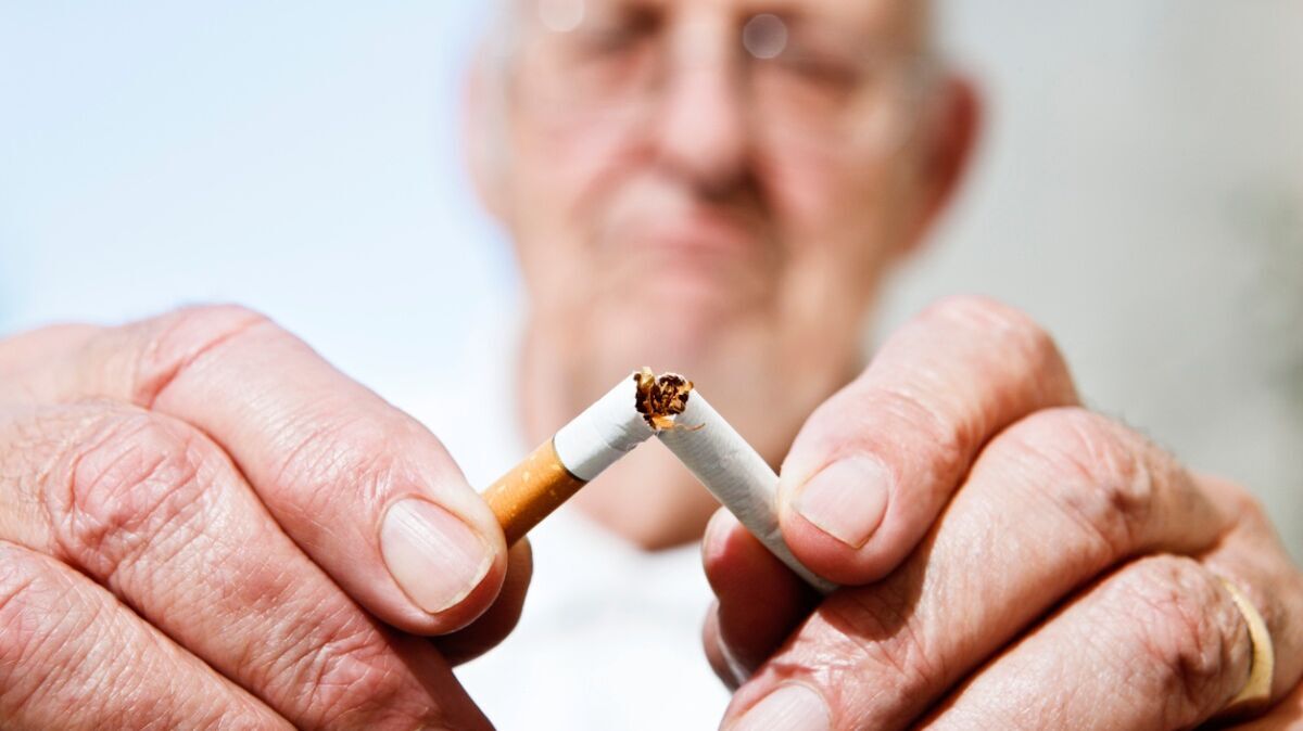 Ein älterer Mann mit Brille zerbricht eine Zigarette.
