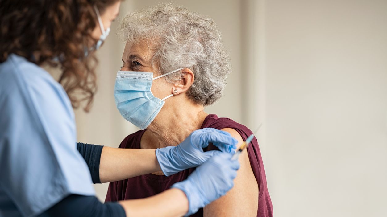 Ältere Frau erhält von medizinischem Personal eine Spritze in den Oberarm.