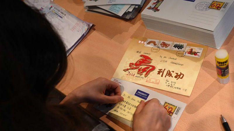 Eine Frau klebt ein Post-it auf einen Brief mit asiatischen Schriftzeichen 