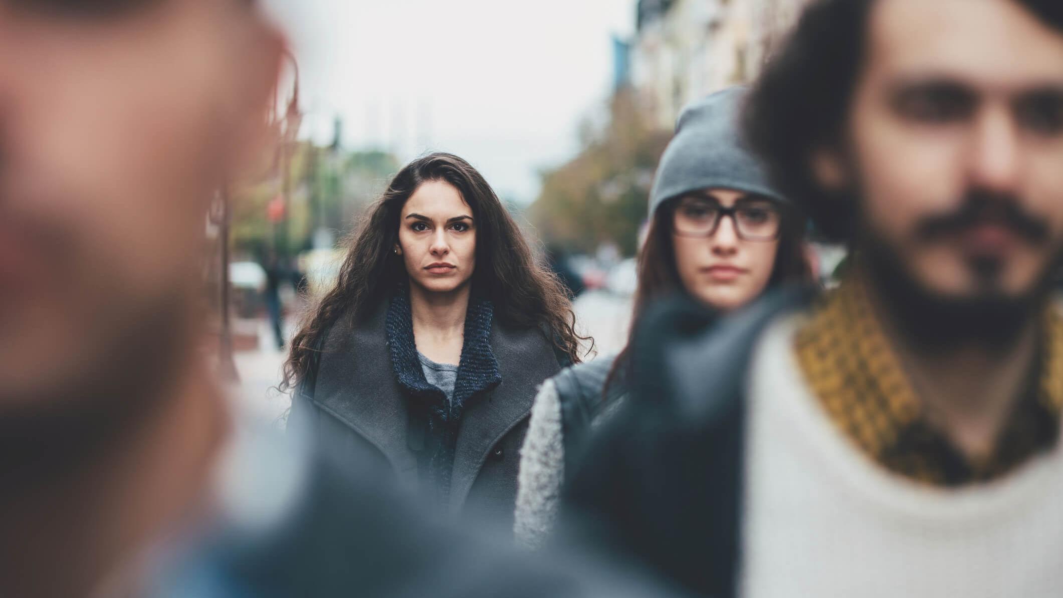 Eine junge Frau sieht unglücklich aus in einer Gruppe junger Menschen