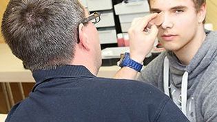 Ein Helfer des RUD-Teams schminkt eine Augenverletzung bei einem Verletztendarsteller.