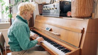 Junge blonde Frau spielt auf einem alten Klavier