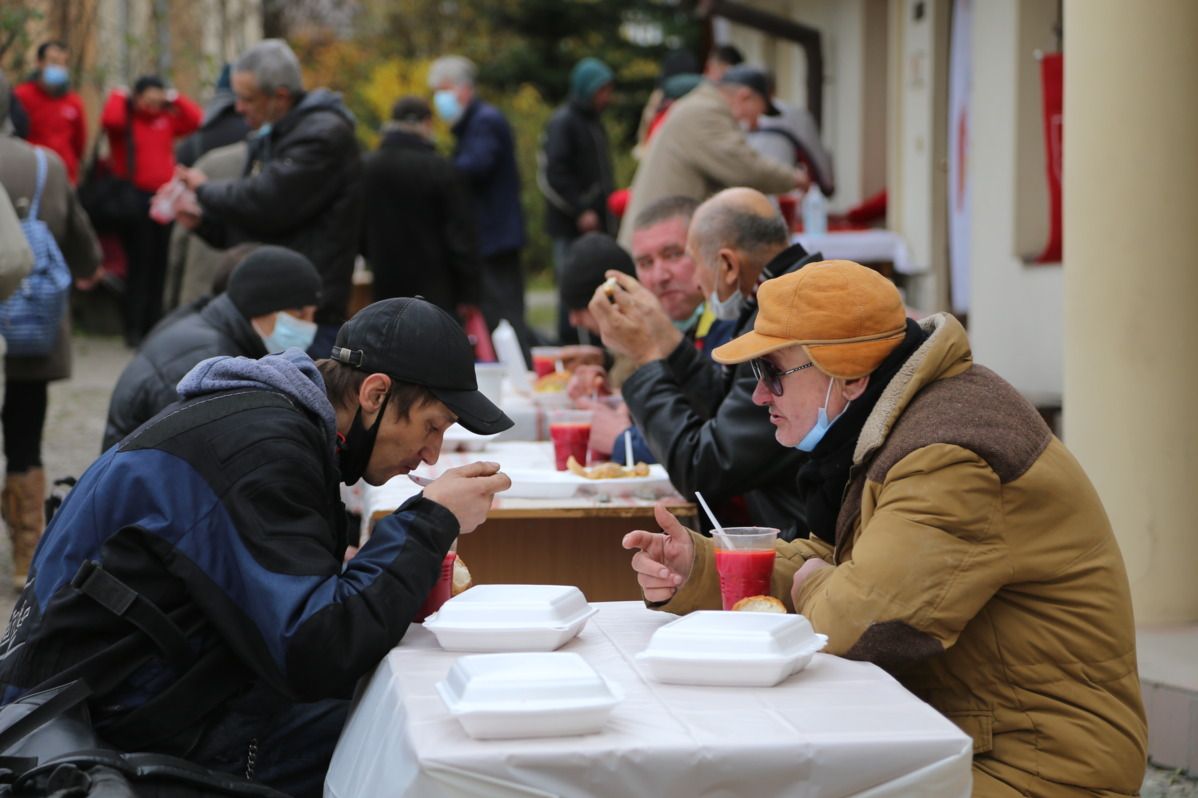 Ukrainische Menschen wärmen sich am Essen der Malteser.