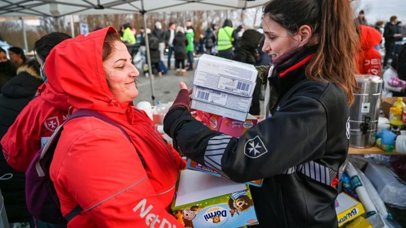 Eine Frau überreicht einer anderen Frau Lebensmittelpakete