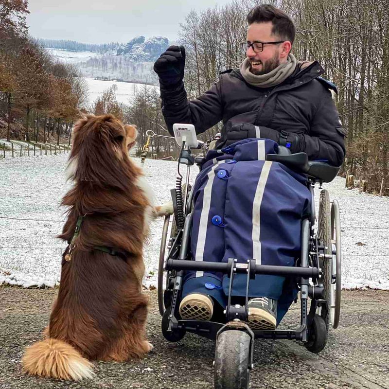 Ein Mann im Rollstuhl mit einem Hund in einem Park