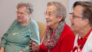 Drei ältere Damen lachen gemeinsam beim Malteser Seniorentreff.