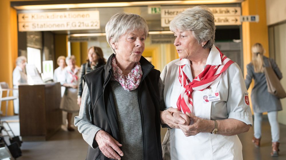 Zwei ältere Damen laufen durch einen Krankenhausflur.