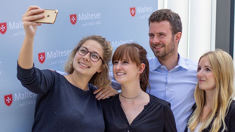 Es werden vier Trainees der Malteser gezeigt, welche ein Selfie machen.