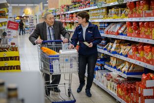 Ehrenamtliche hilft Senior beim Einkaufen im Supermarkt